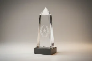 Faceted crystal award with star and laurel etching on a slate base, centered on a soft neutral gradient background.
