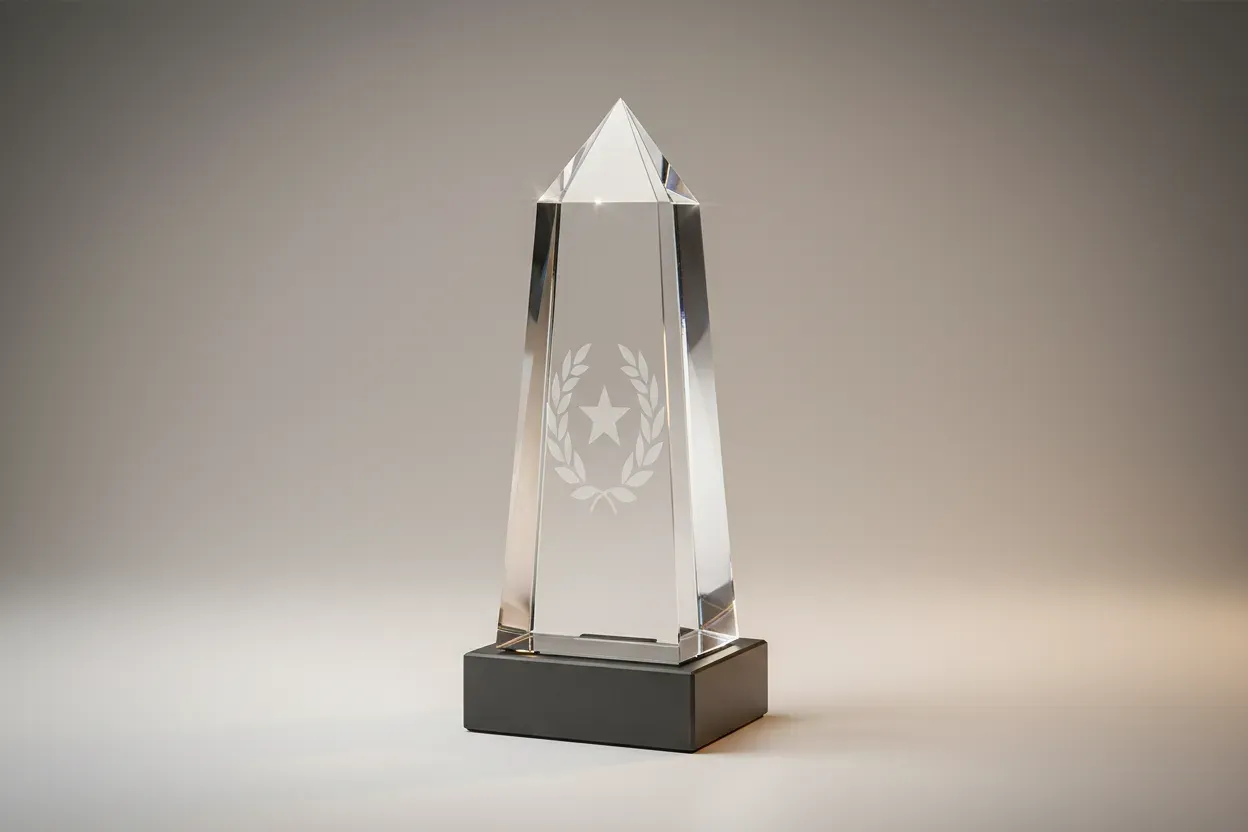 Faceted crystal award with star and laurel etching on a slate base, centered on a soft neutral gradient background.